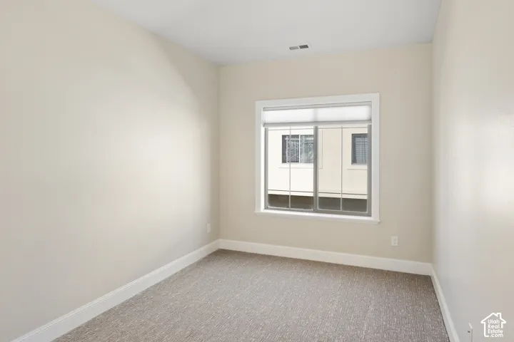 2nd Bedroom with neutral-toned interior space featuring light-colored wall paint, plush carpeting, and a sliding window with installed window treatment