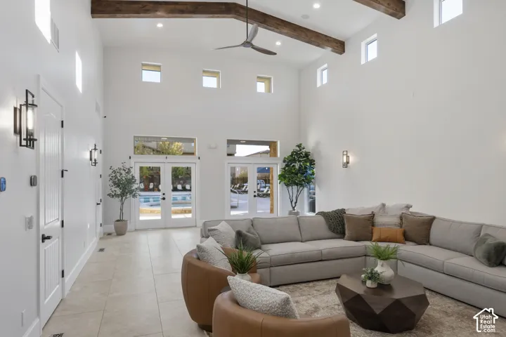 Vaulted ceilings featuring exposed wood beams, neutral ceramic tile flooring, clerestory windows, and dual sets of glass-paned French doors