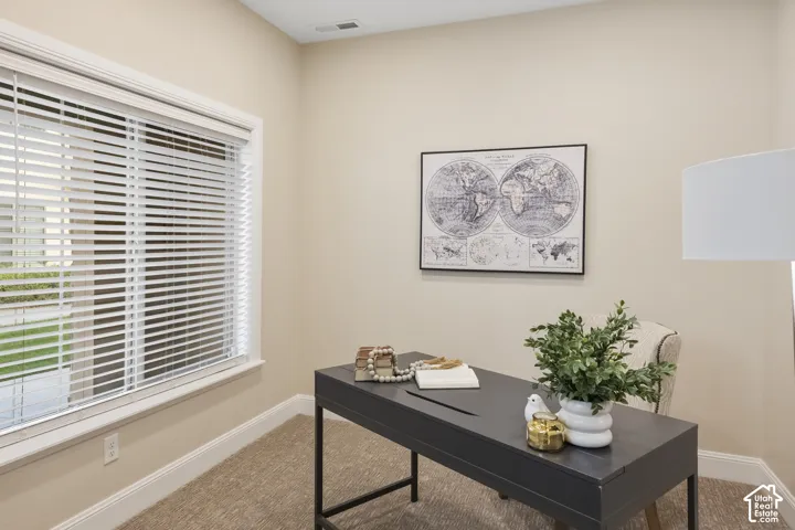 Home Office off the main entry with neutral-toned room featuring high-profile window casing, horizontal slat blinds, and wall-to-wall carpeting