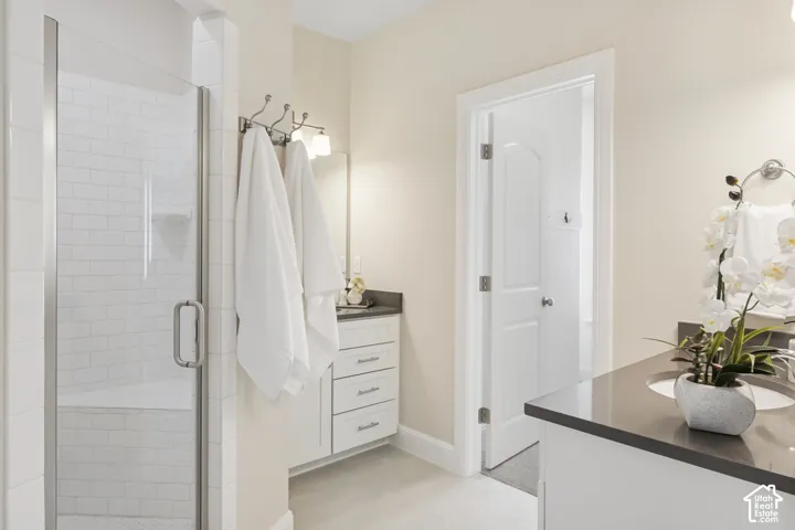 Primary bathroom featuring a glass-enclosed dual shower heads with white subway tile surround, white cabinetry, solid-surface countertops with integrated sinks, and brushed-nickel hardware
