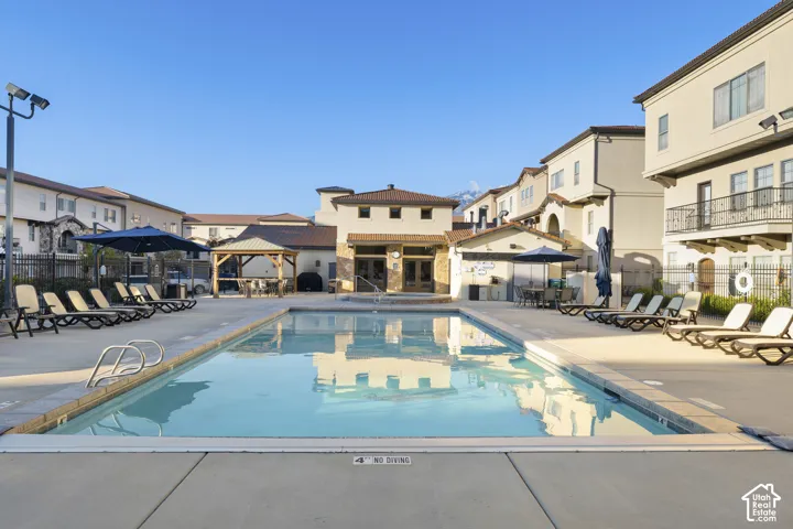 Swimming pool with concrete decking, covered gazebo, and stucco exterior buildings