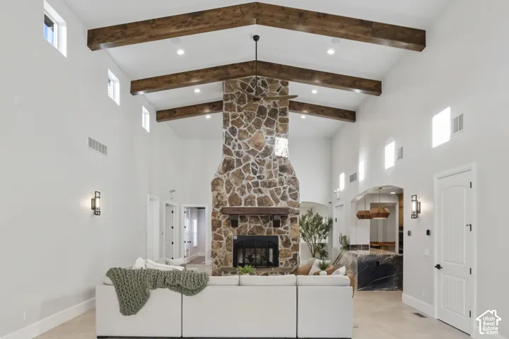 Vaulted ceiling with exposed wood beams, floor-to-ceiling stone fireplace, heavy wood mantel, recessed lighting, and clerestory windows