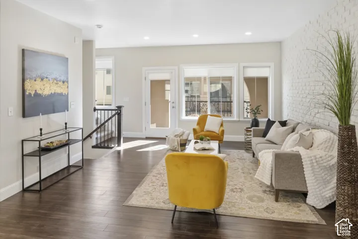 Living area featuring wood-finish flooring, a painted brick accent wall, recessed lighting and covered balcony