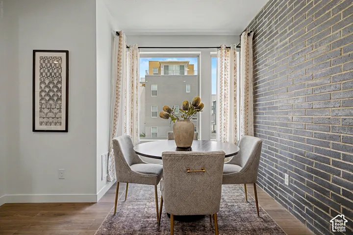 Accent wall featuring gray-toned brick masonry, wood-finish flooring, and large window configuration