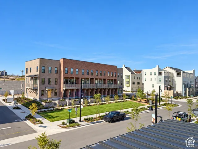 Multi-story brick exterior building featuring private balconies, stone retaining walls, professional landscaping, and manicured lawns