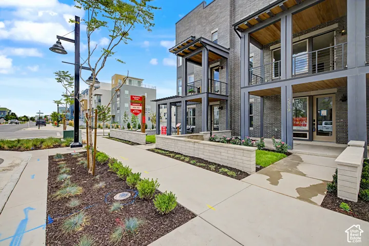 Multi-level exterior featuring dark brick masonry, metal-framed balconies, integrated wood-finish ceiling soffits, and limestone-capped retaining walls