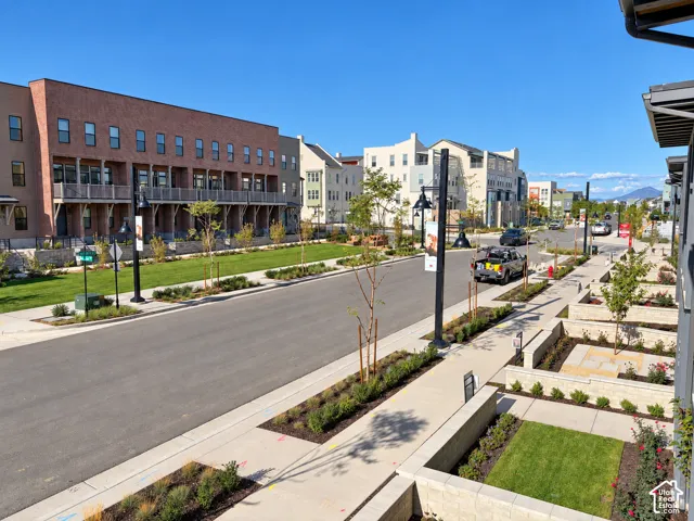 Streetscape featuring brick multi-level architecture, paved sidewalks, manicured grass lawns, ornamental landscaping, and modern street lighting