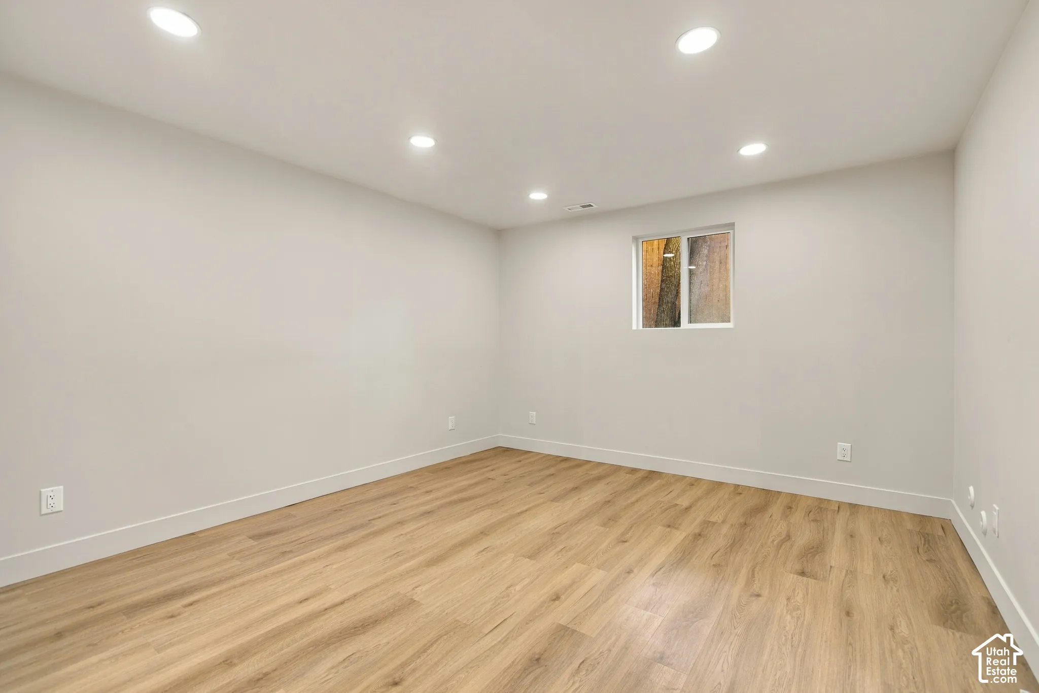 Neutral-toned interior featuring wood-finish flooring, recessed lighting, and a window with exterior visibility