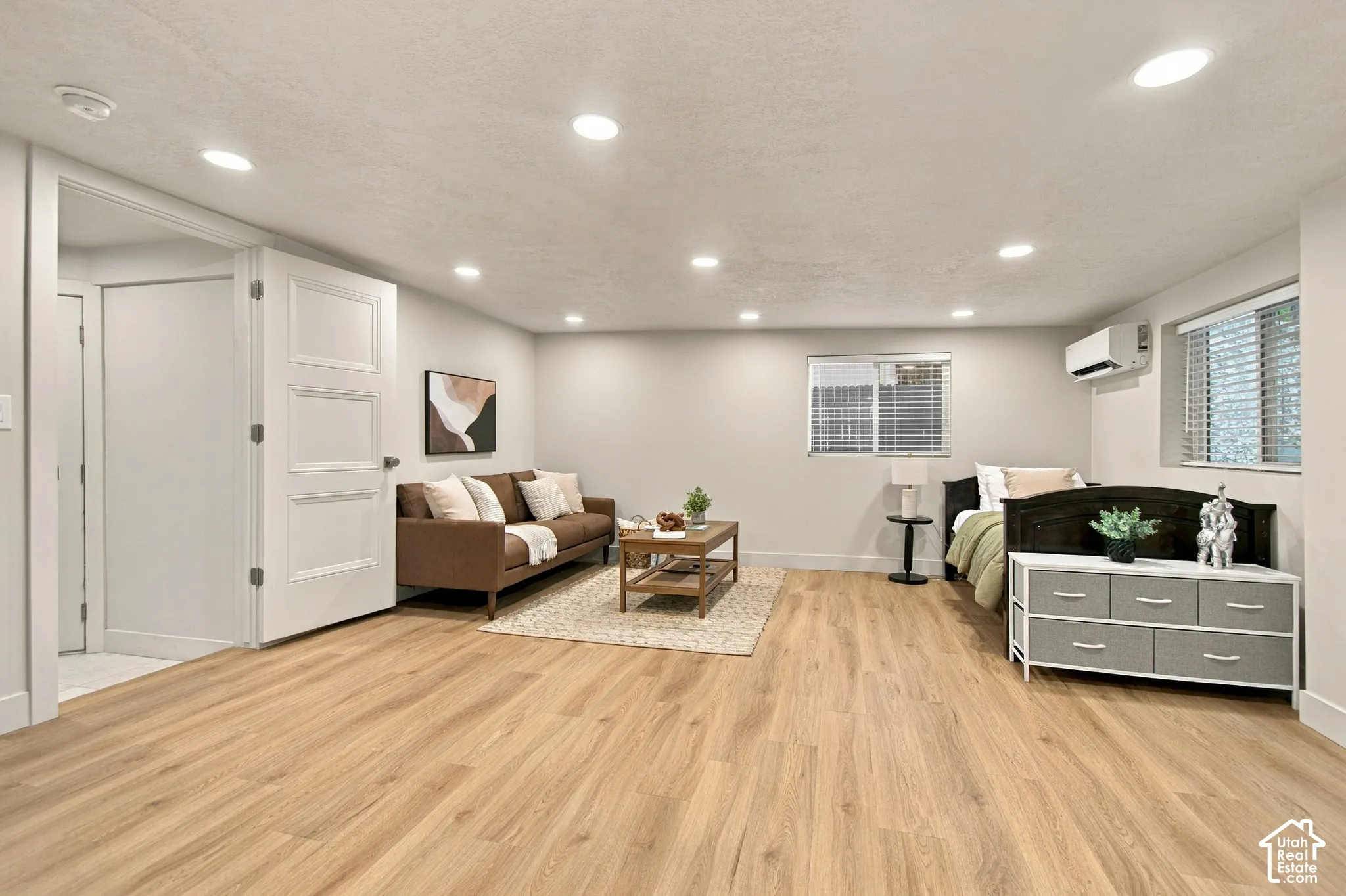 Neutral-toned interior space featuring wood-finish flooring, recessed lighting, double-panel interior doors, and a wall-mounted climate control unit