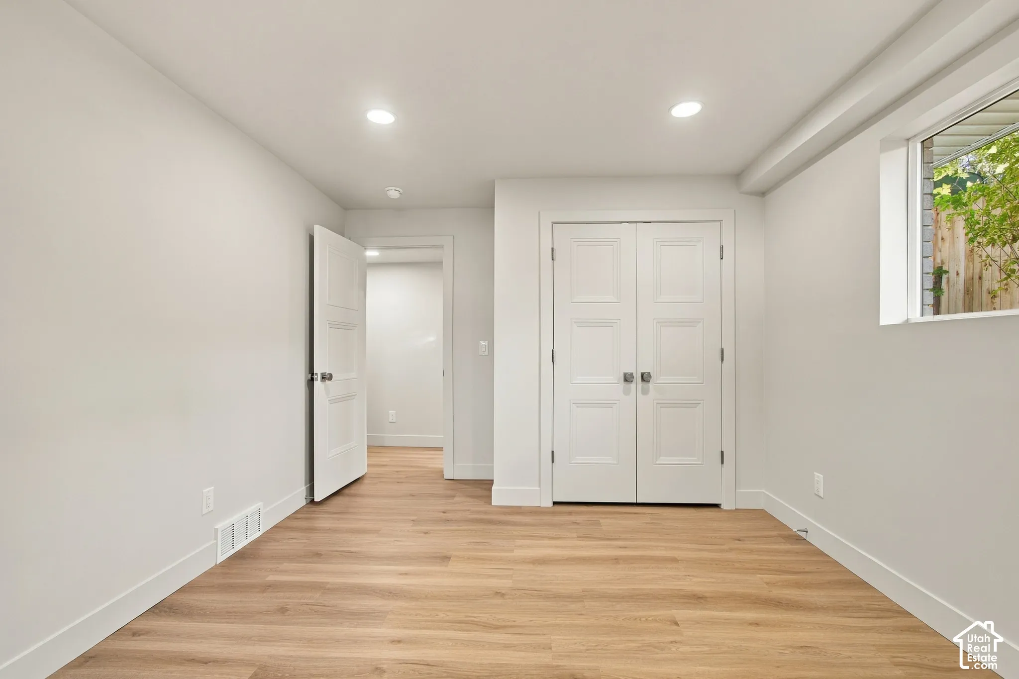 Neutral interior featuring wood-finish flooring, recessed lighting, white three-panel interior doors, and a double-door closet