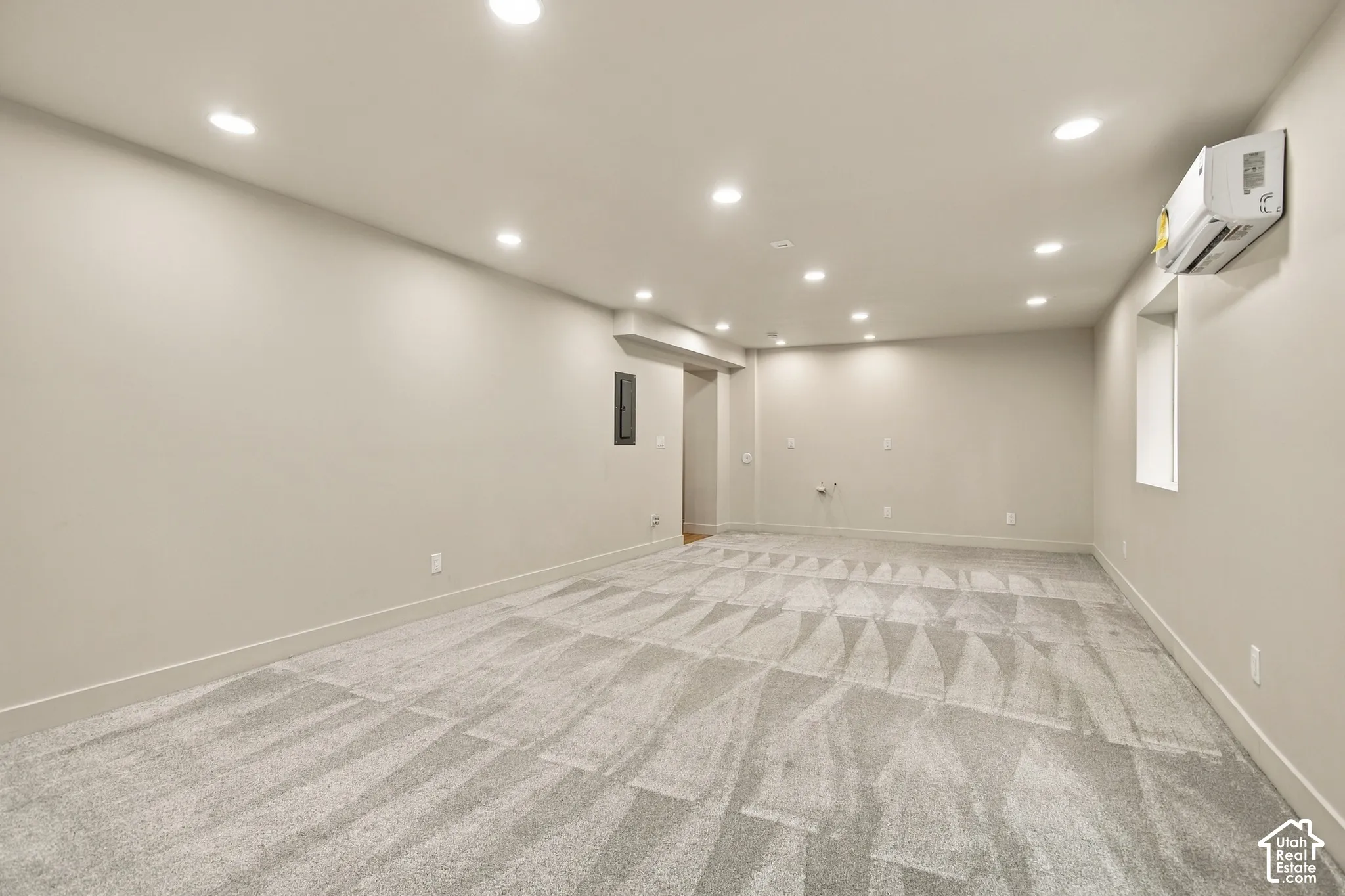 Neutral-toned interior featuring wall-to-wall carpeting, recessed ceiling lighting, and a wall-mounted ductless heating and cooling unit