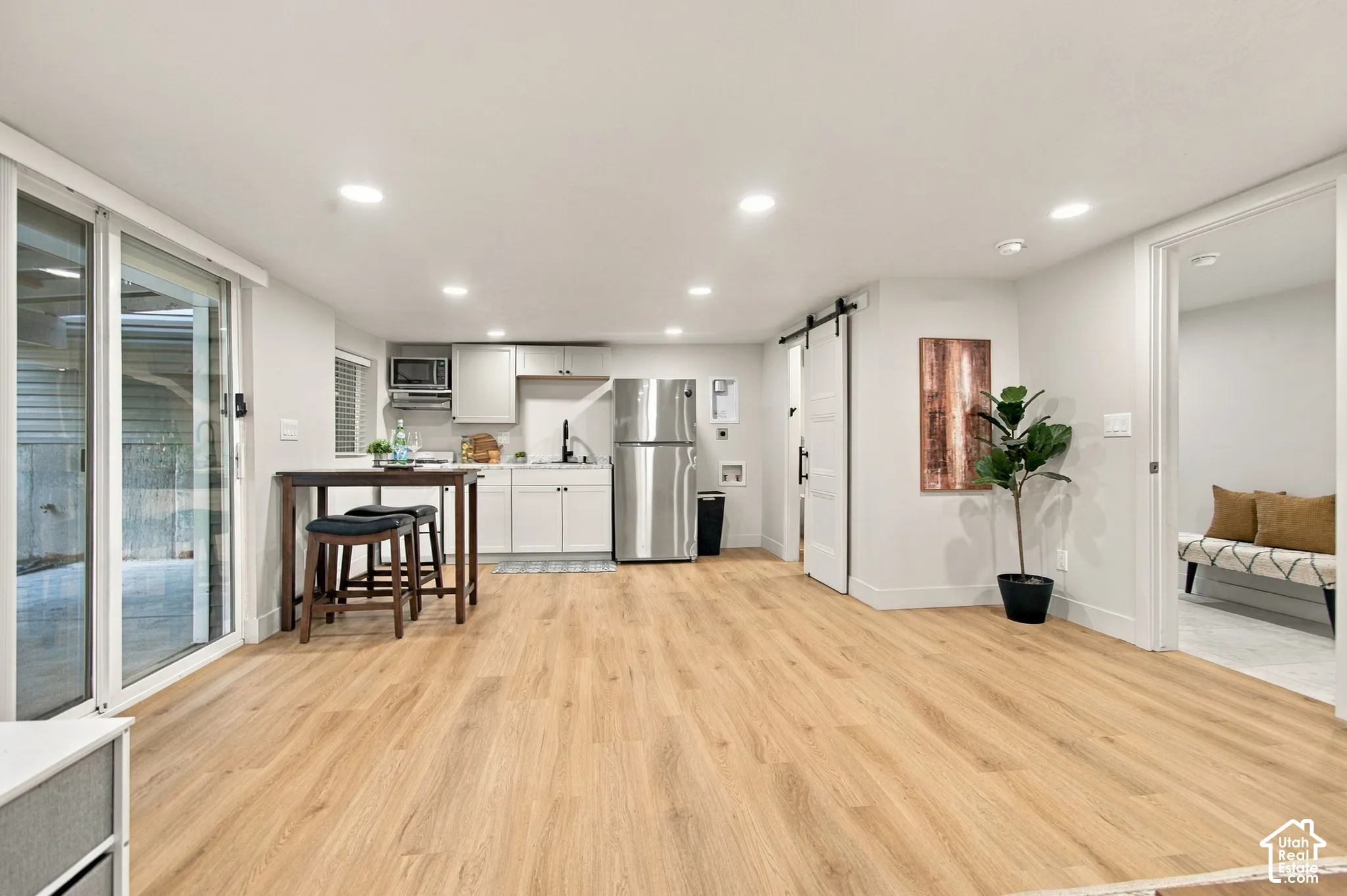 Kitchenette featuring white cabinetry, stainless steel appliances, wood-finish flooring, recessed lighting, and a sliding barn door