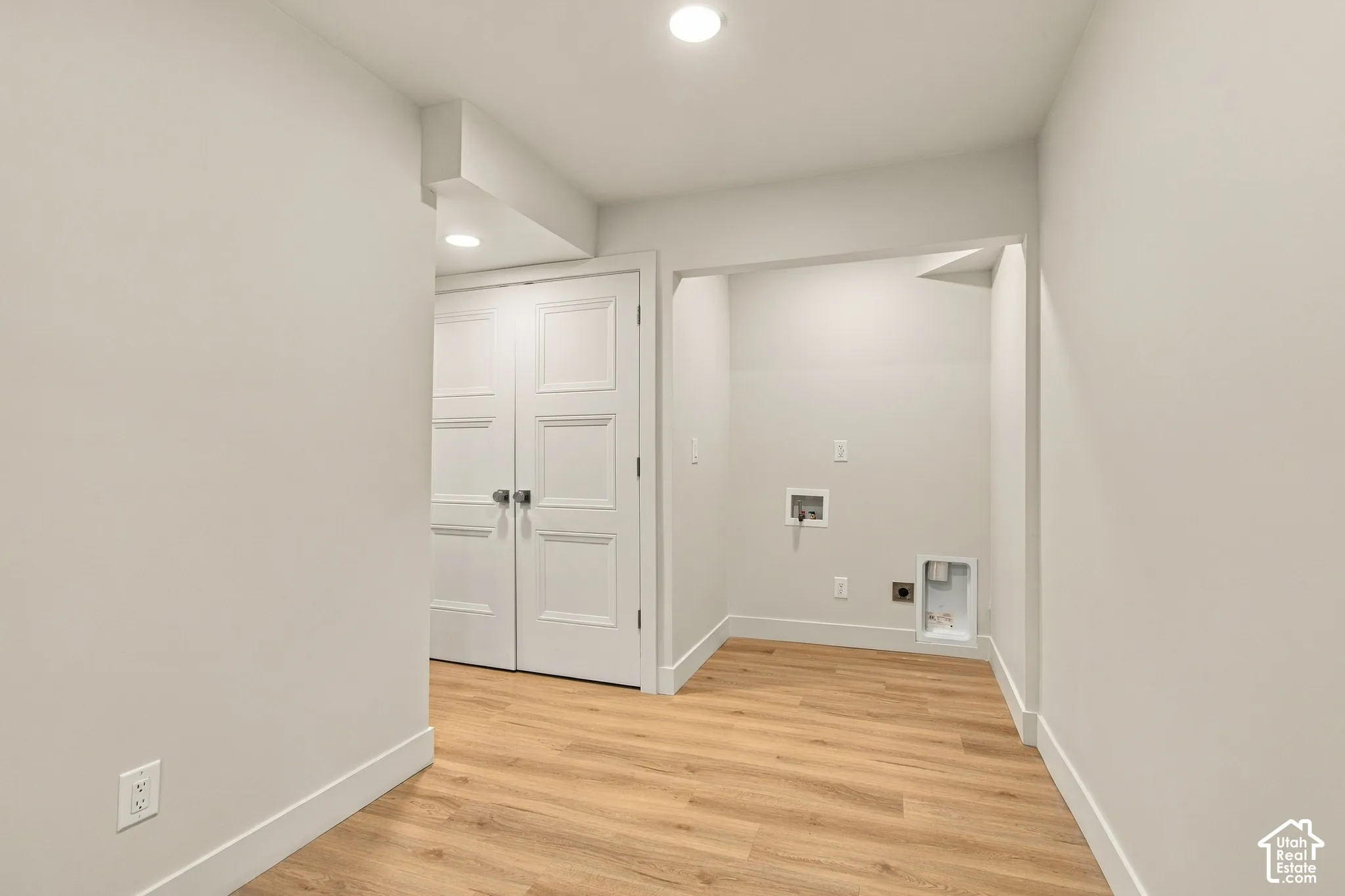 Utility area featuring wood-finish flooring, recessed lighting, and white three-panel interior double doors