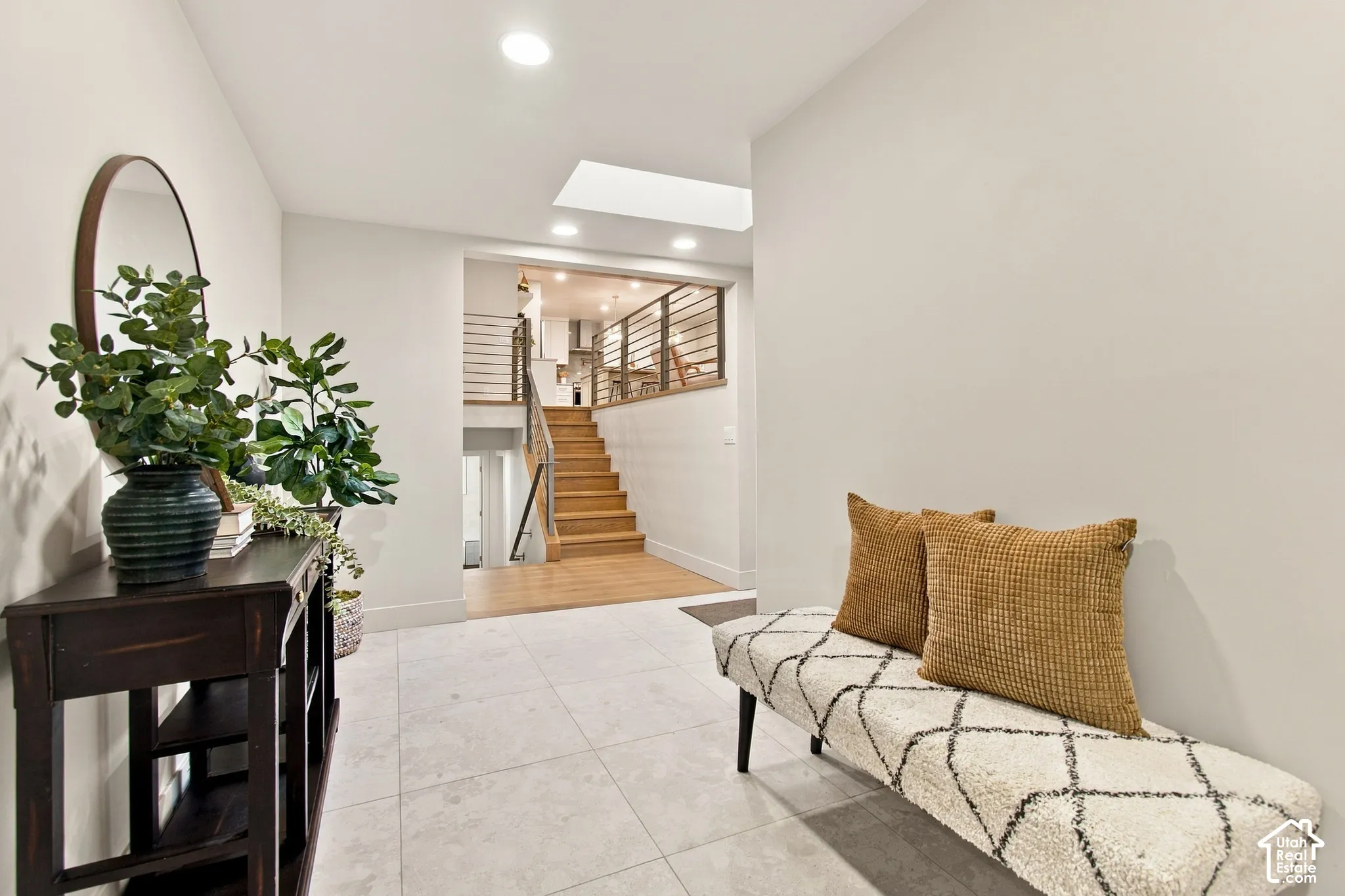 Entryway featuring large-format tile flooring, wood-finish staircase, horizontal metal railing, and recessed ceiling lighting