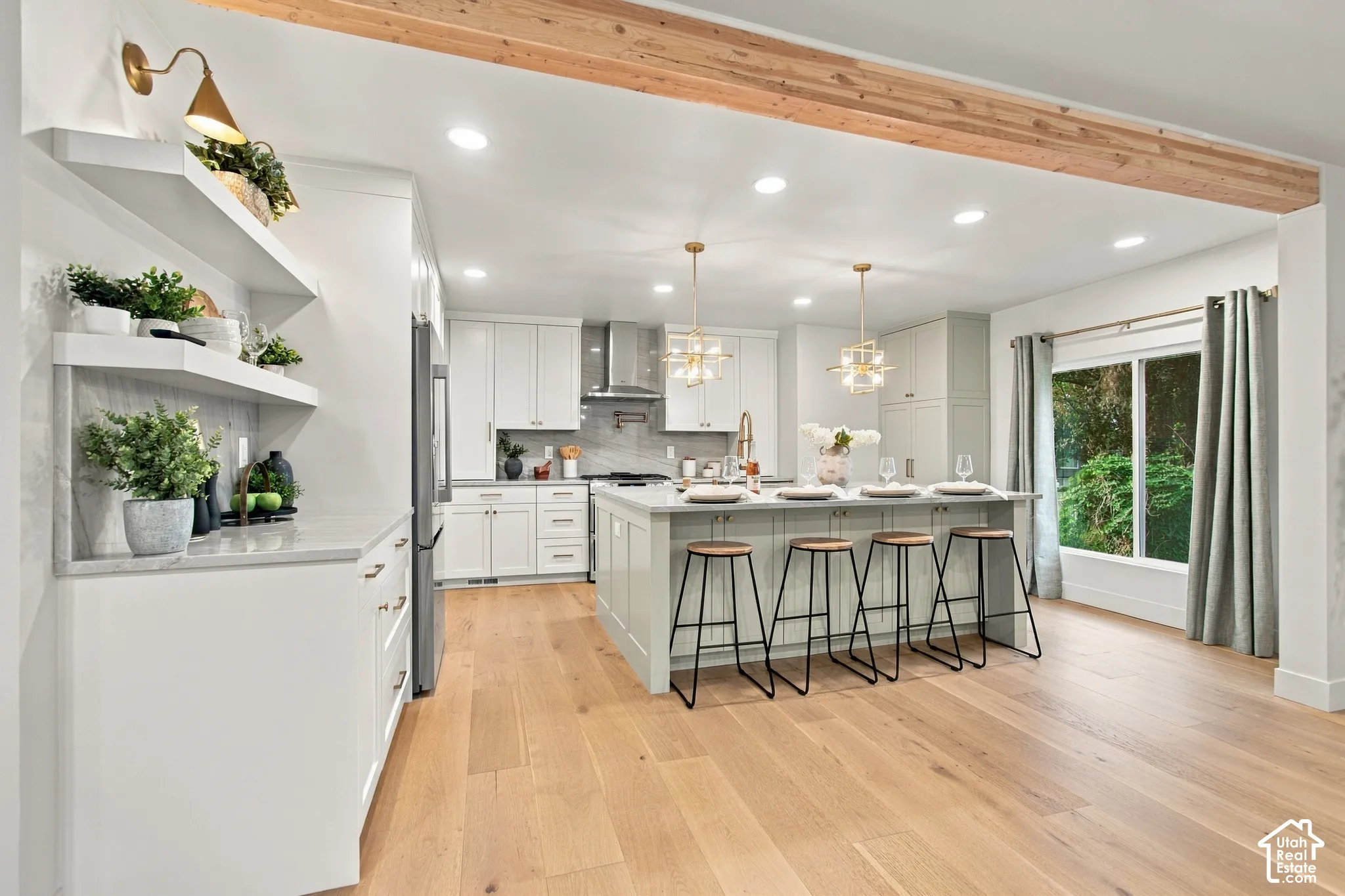 Kitchen featuring wood-finish flooring, a central island with seating, shaker-style cabinetry, a stone-finish backsplash, and an exposed structural wood beam