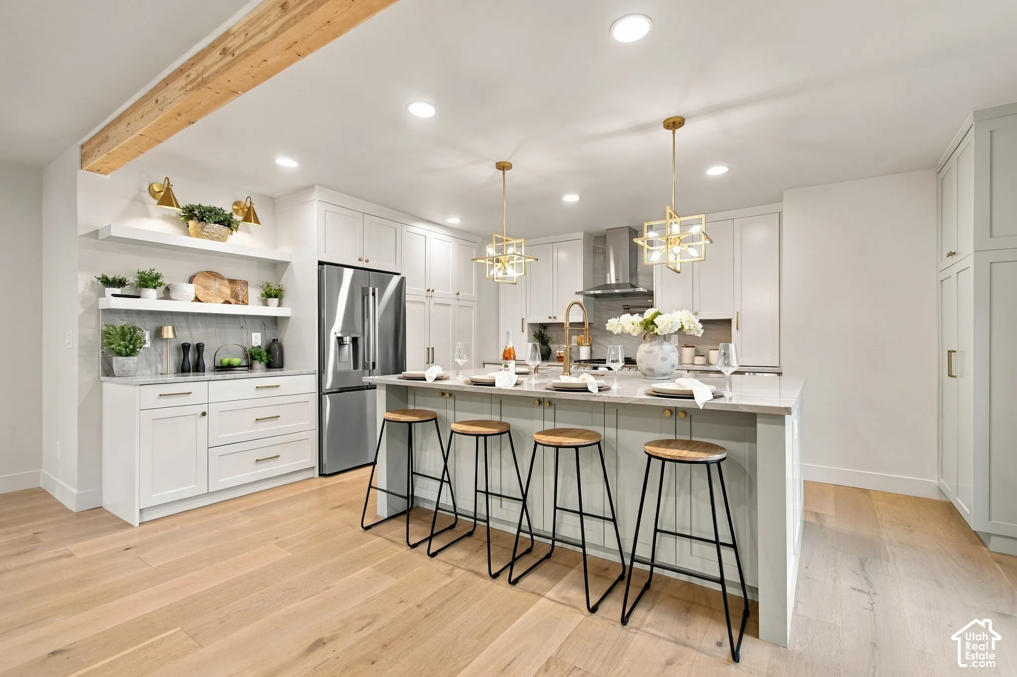 Kitchen featuring wood-finish flooring, a central island with a quartz countertop, white shaker-style cabinetry, recessed ceiling lighting, and a prominent exposed wood beam