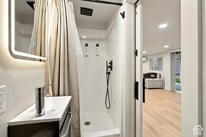Bathroom featuring a backlit vanity mirror, chrome faucet, white countertop, walk-in shower with a matte black handheld showerhead, and a sliding barn-style door