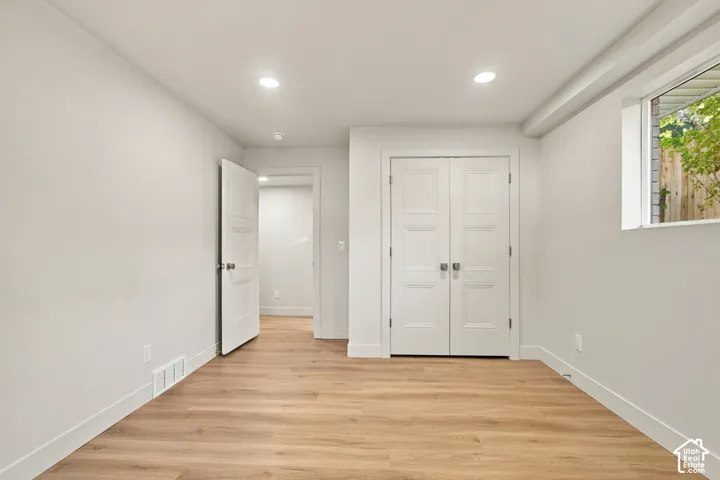 Neutral interior featuring wood-finish flooring, recessed lighting, white three-panel interior doors, and a double-door closet