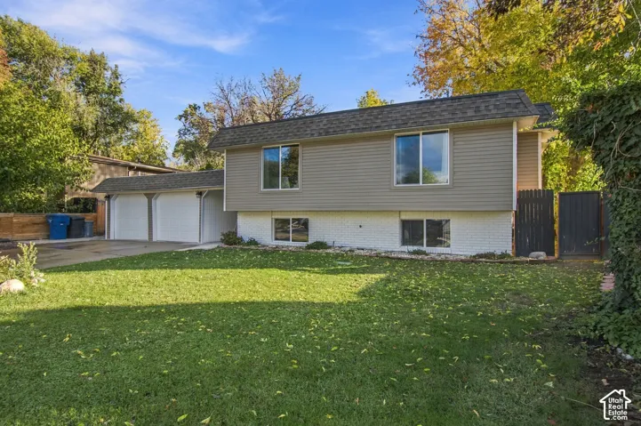 Split-level exterior featuring a combination of horizontal siding and painted masonry, a two-car garage, and mature landscaping