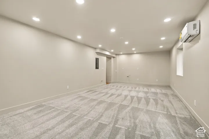 Neutral-toned interior featuring wall-to-wall carpeting, recessed ceiling lighting, and a wall-mounted ductless heating and cooling unit