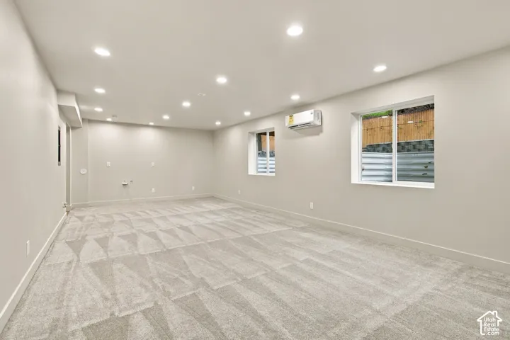 Neutral interior featuring wall-to-wall carpeting, recessed ceiling lighting, dual windows, and a wall-mounted ductless climate control unit