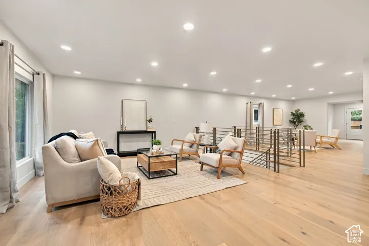 Open-concept living space featuring wood-finish flooring, recessed lighting, and a metal horizontal-bar stair railing