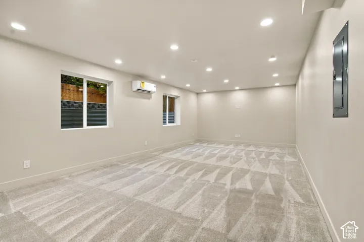 Interior space featuring neutral wall-to-wall carpeting, recessed ceiling lighting, and a wall-mounted ductless climate control unit