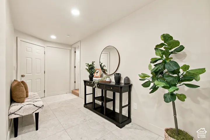 Neutral-toned tile flooring, recessed ceiling lighting, and a six-panel interior door