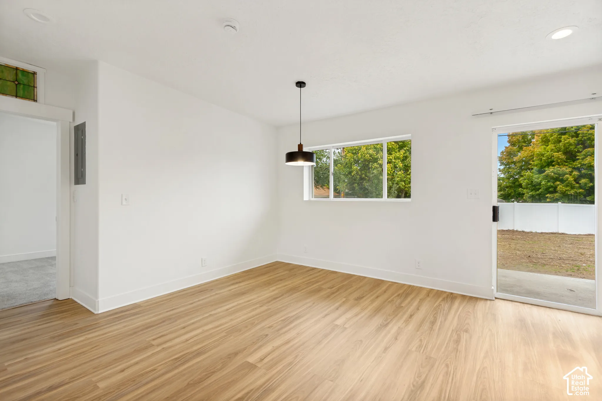 Interior space featuring lvp wood-finish flooring, recessed lighting, a modern drum pendant fixture, and a sliding glass door providing external access