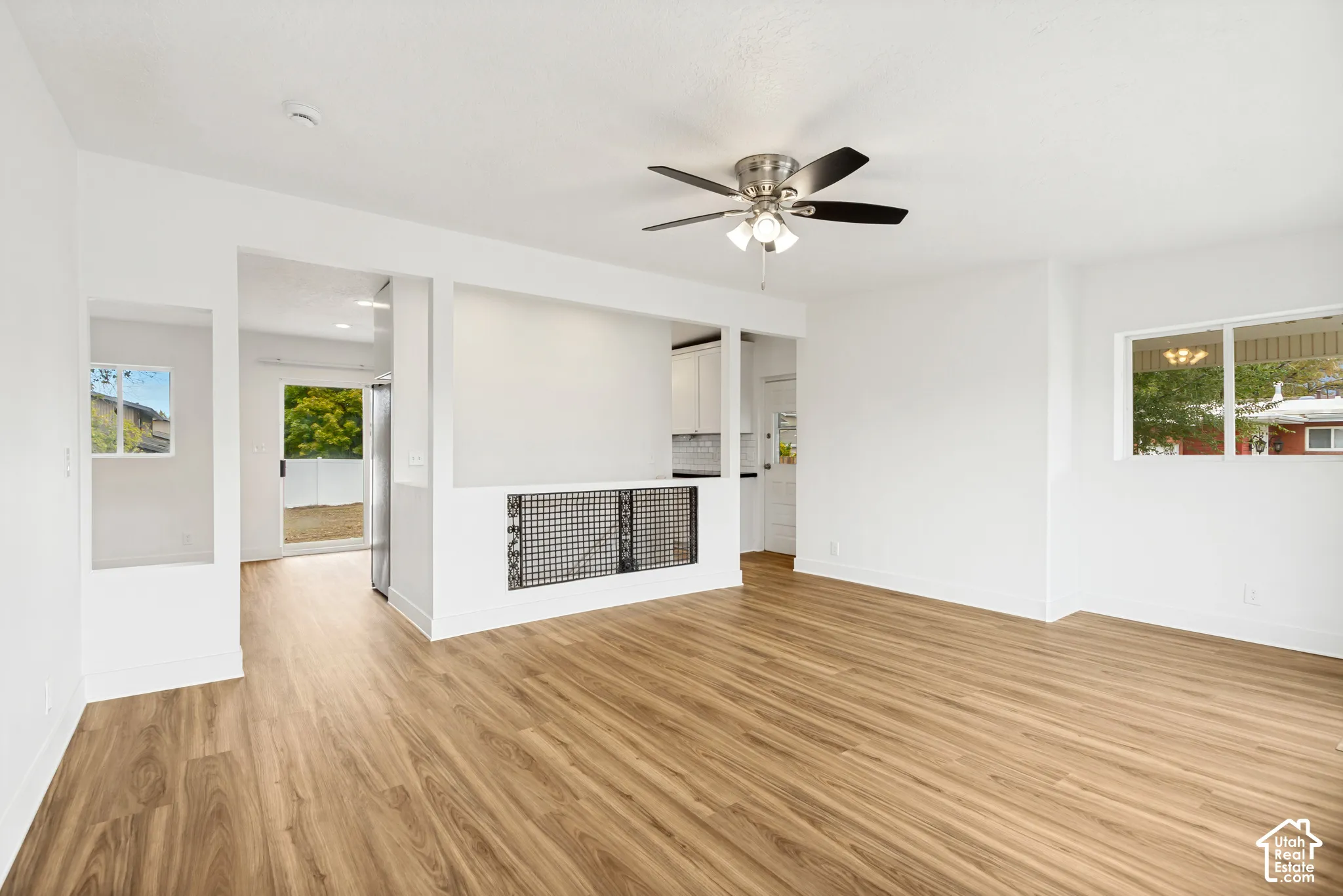 Interior space featuring wood-finish flooring, a ceiling fan with integrated lighting, and a metal grid stair railing
