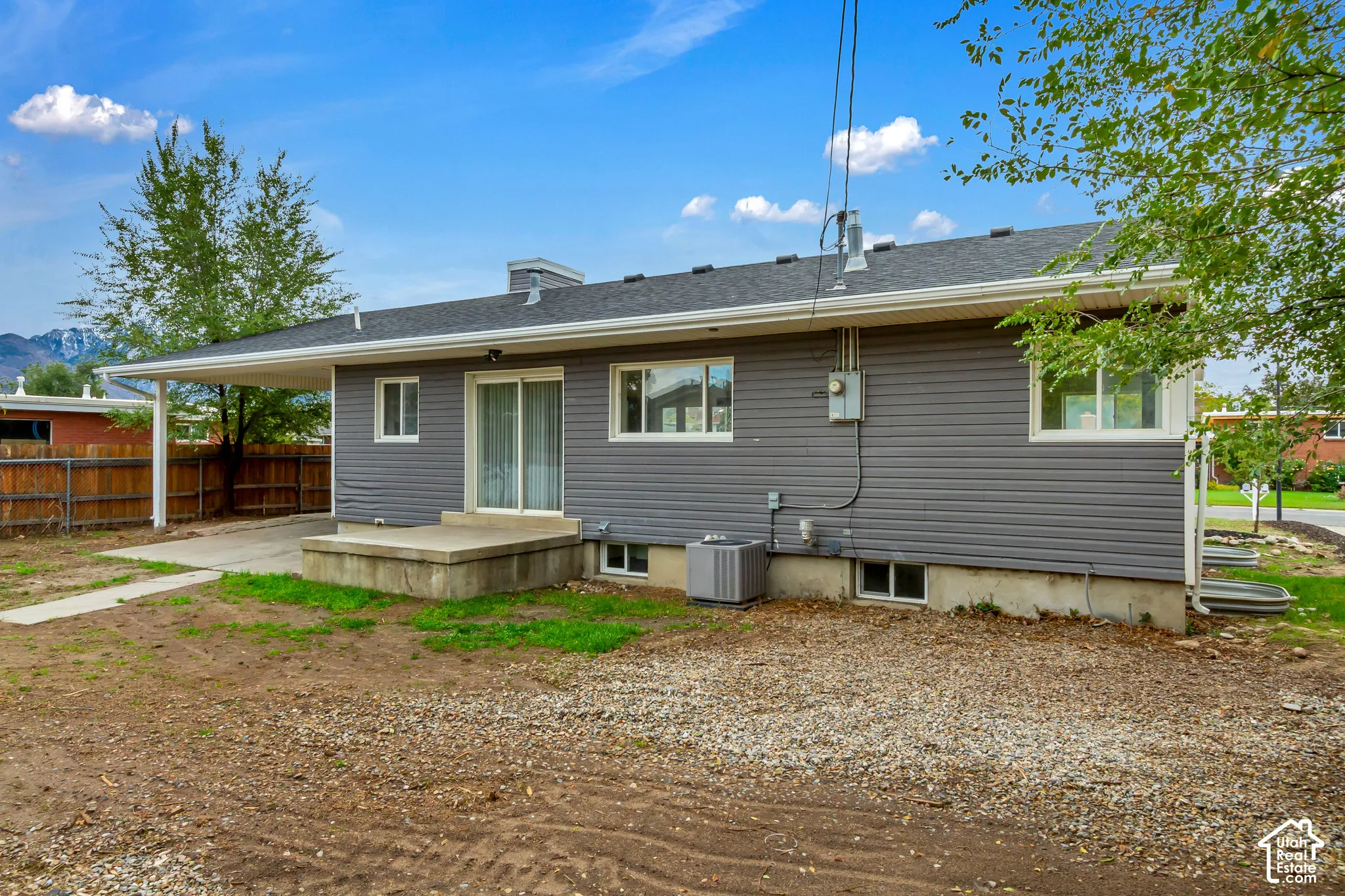 Exterior featuring horizontal siding, asphalt shingle roof, attached carport, concrete patio, and sliding glass door