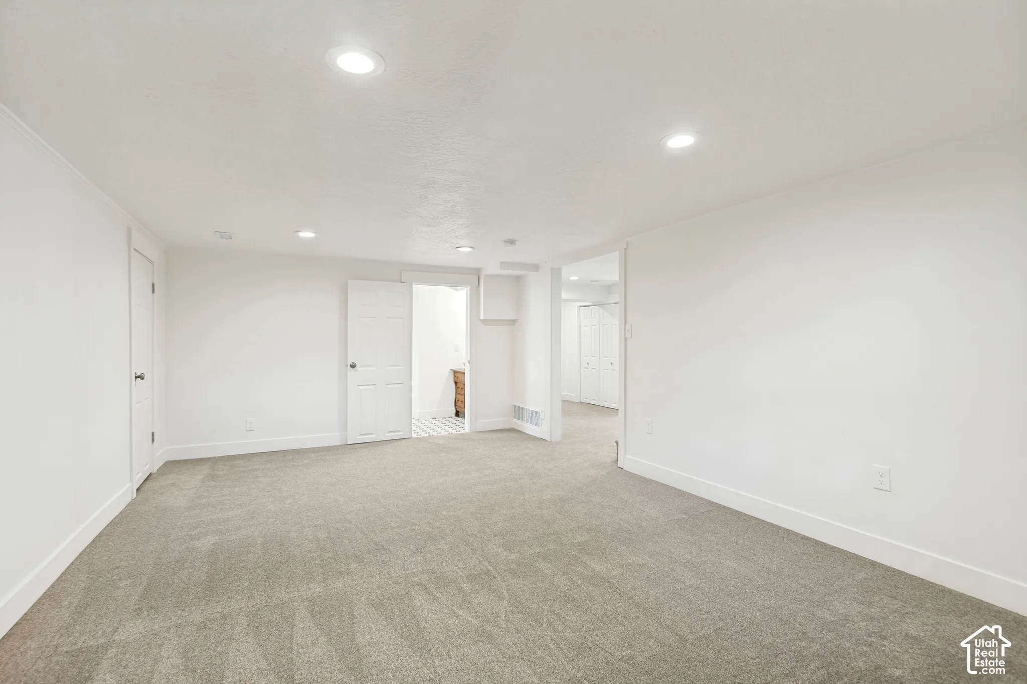 Open interior room featuring wall-to-wall carpeting, recessed ceiling lighting, and multi-panel interior doors