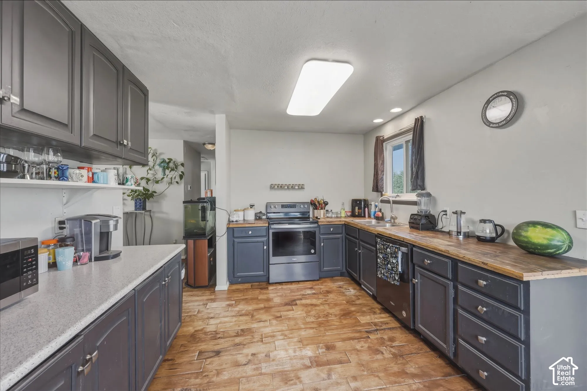 Kitchen featuring dark-toned cabinetry, wood-finish flooring, butcher block countertops, integrated range, and flush-mount ceiling lighting