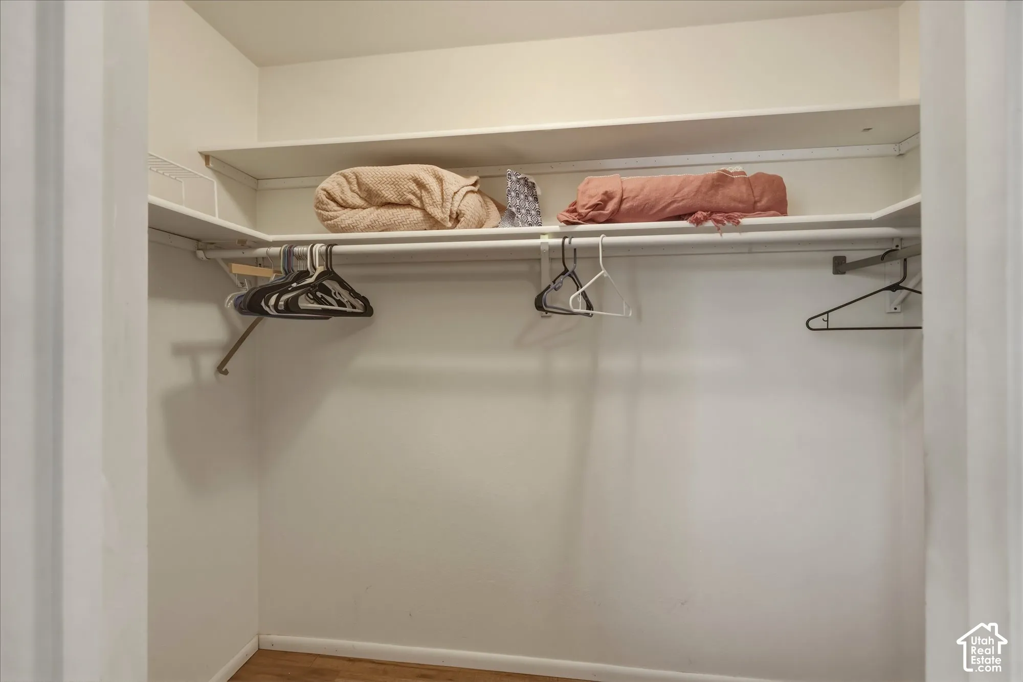 Reach-in closet featuring upper shelving and an integrated hanging rod