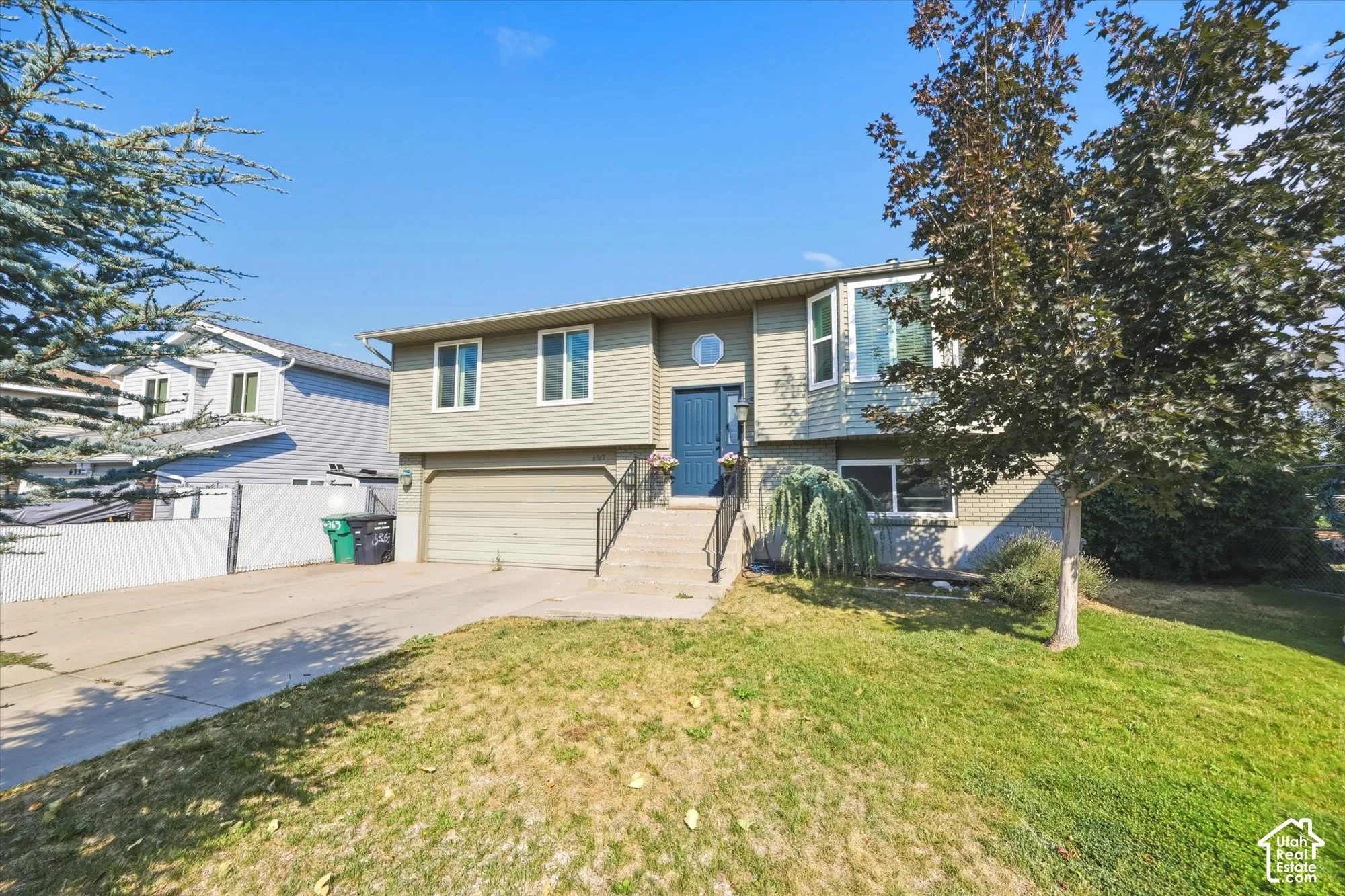 Split-level exterior featuring horizontal lap siding, an attached two-car garage, concrete driveway, and front-facing bay window