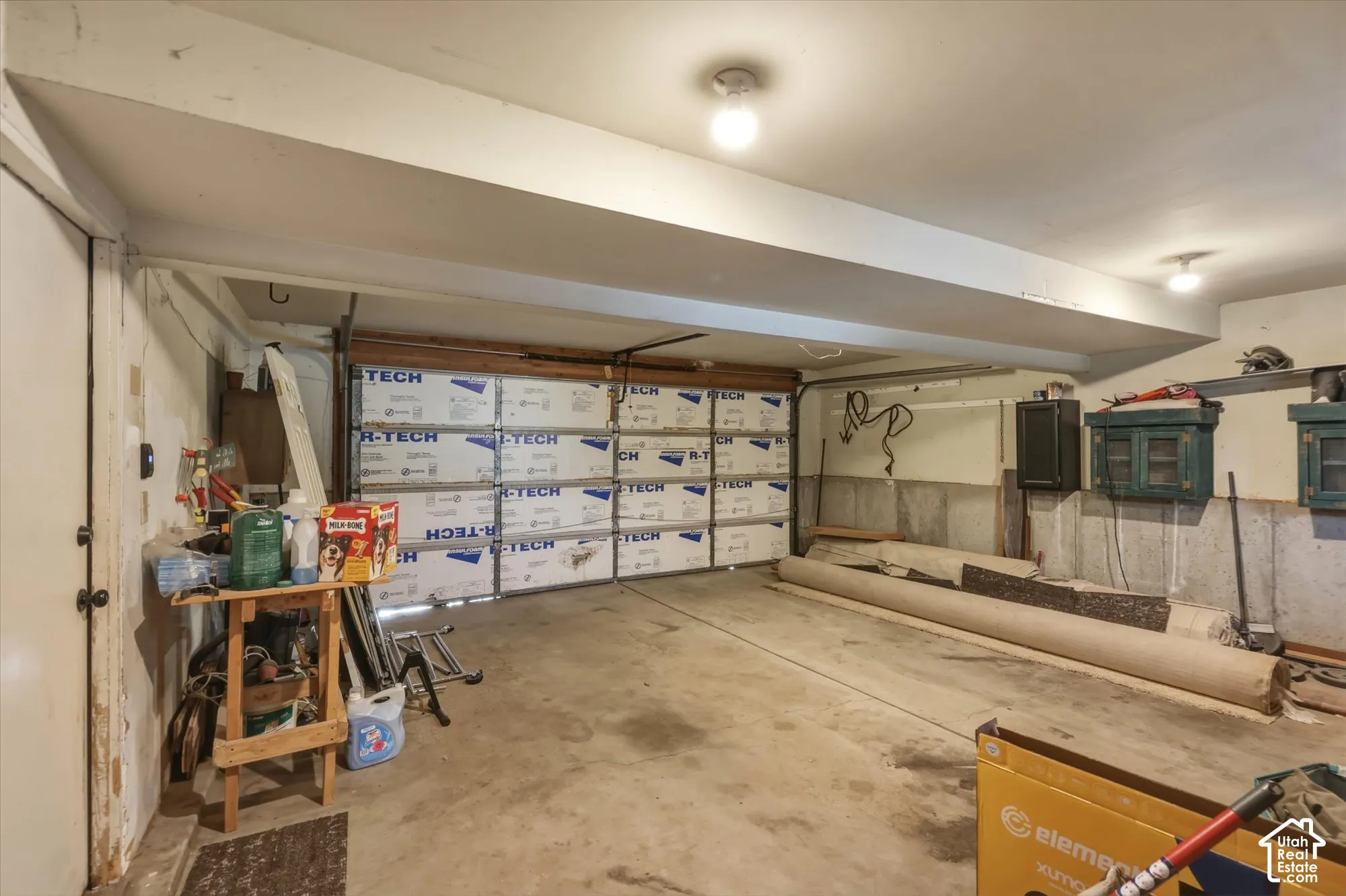 Enclosed garage featuring concrete flooring, insulation-paneled sectional door, and mounted storage cabinetry