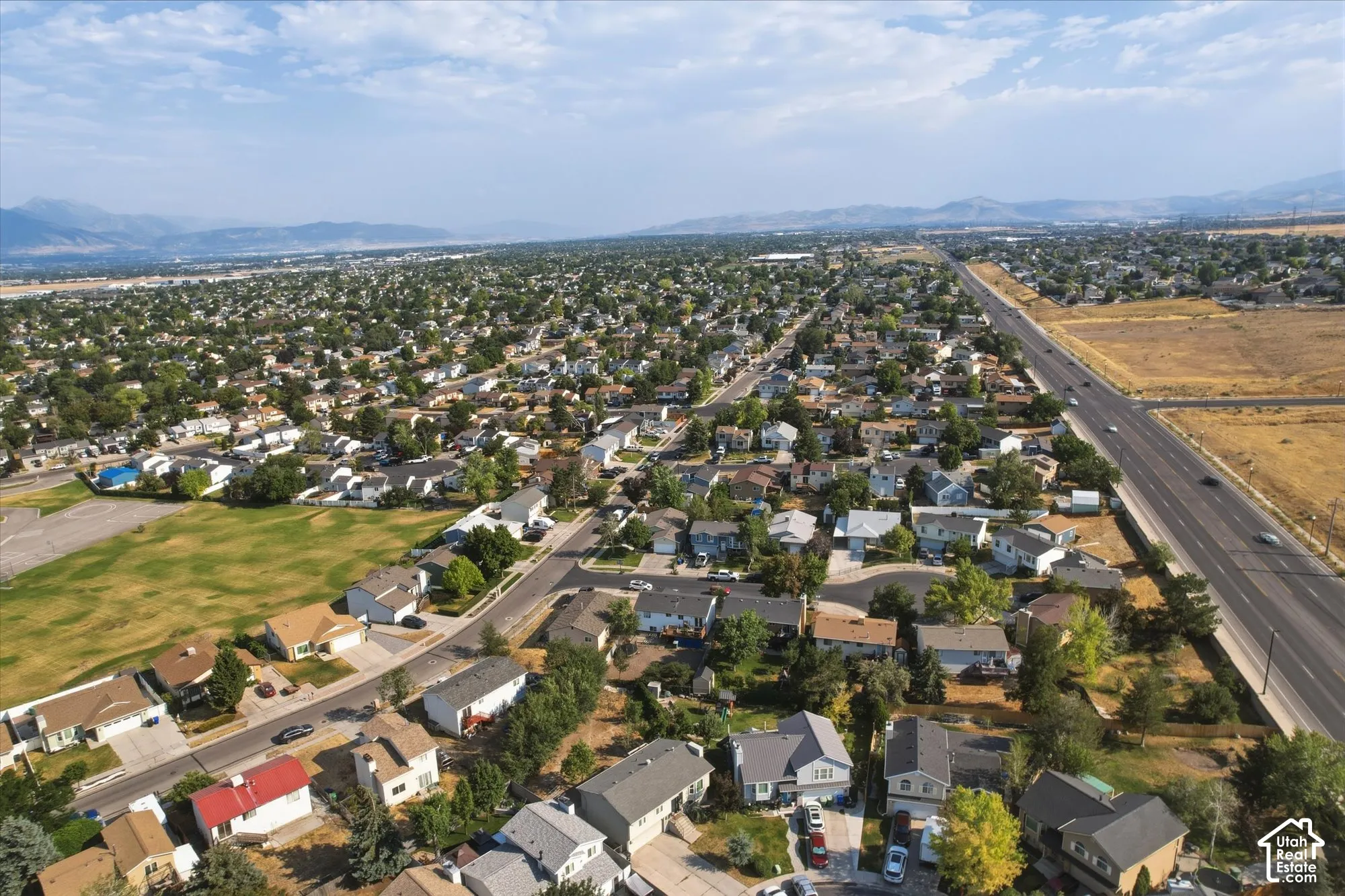 Aerial perspective of a residential neighborhood featuring mature trees and a mountain backdrop