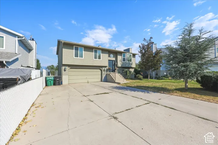 Split-level exterior featuring horizontal siding, a concrete driveway, an integrated two-car garage, and a raised entryway with concrete steps