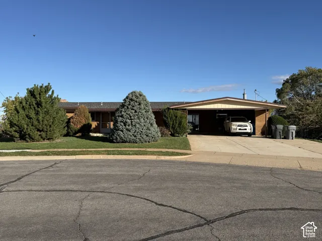 Single-story ranch exterior featuring brick masonry, a covered carport, and a concrete driveway