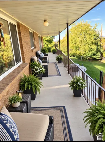 Covered concrete balcony featuring a brick exterior wall, full-length metal railing, and recessed ceiling lighting