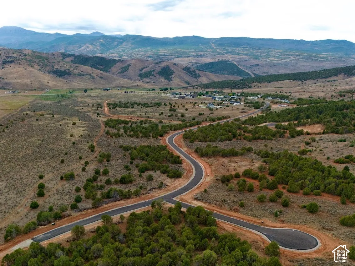 Aerial perspective of expansive land featuring paved roadways, native vegetation, and a prominent mountain range backdrop