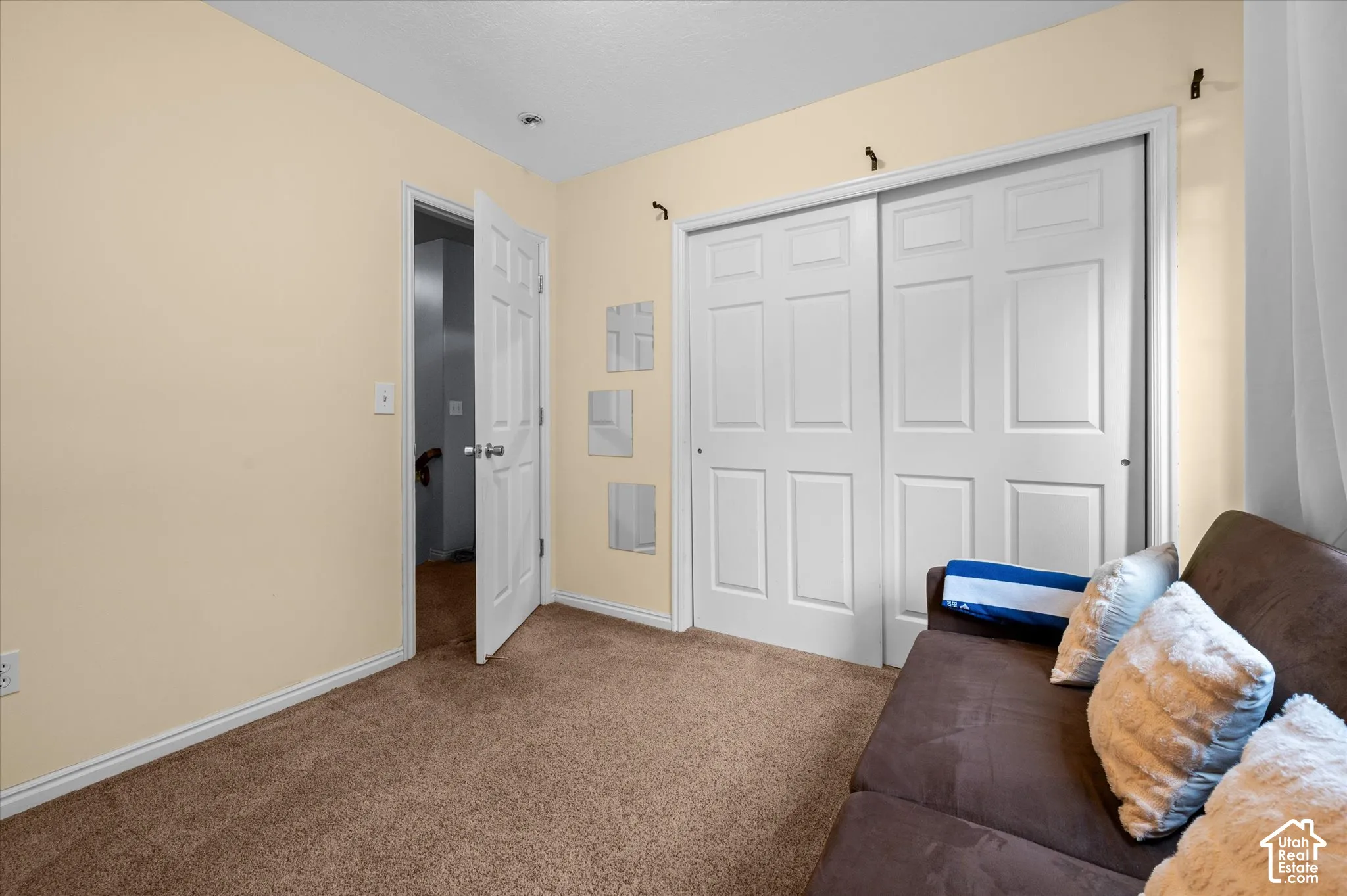 Interior space featuring neutral-toned walls, carpeting, and a closet with white paneled sliding doors