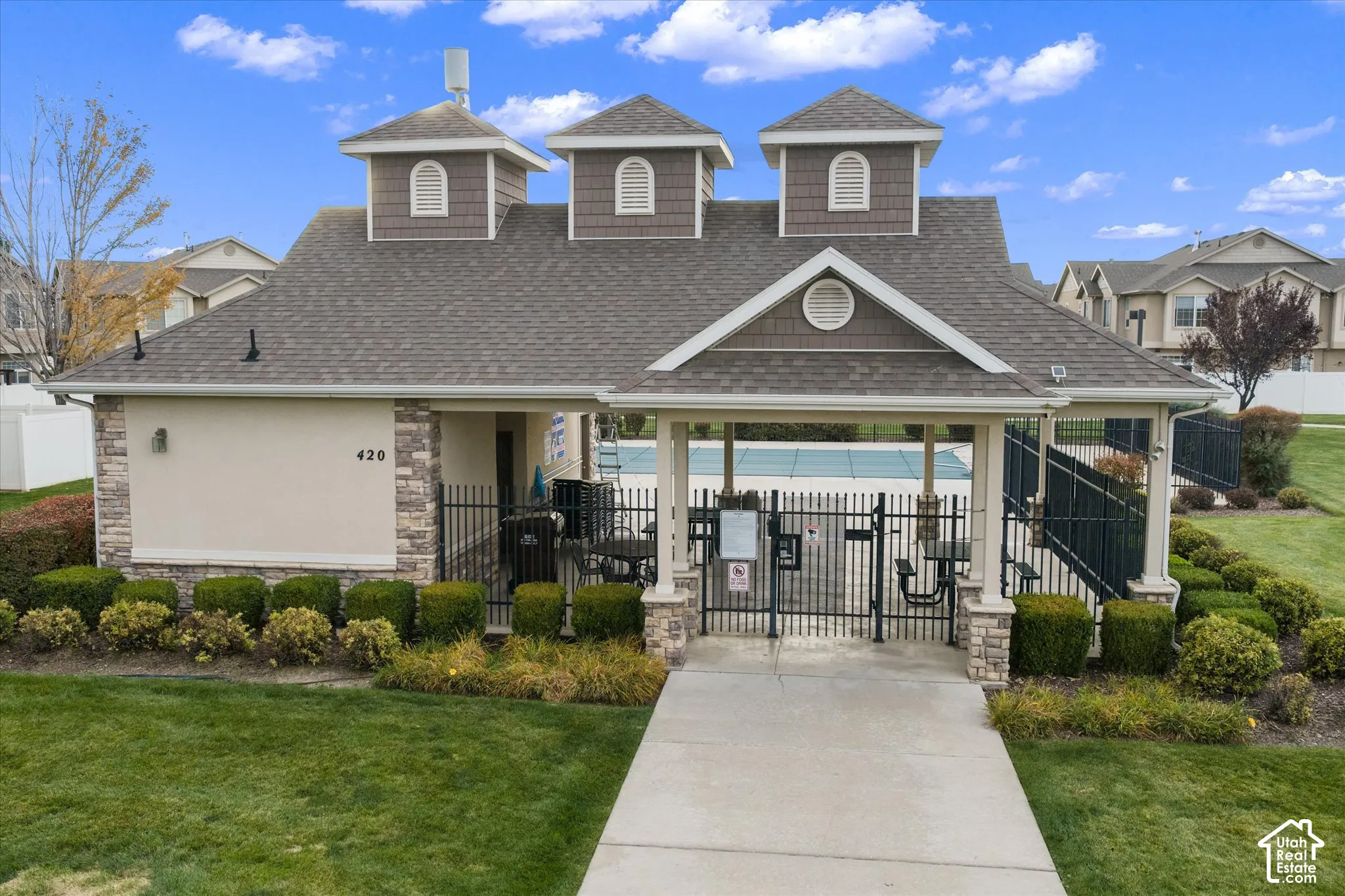 Clubhouse exterior featuring a multi-gabled roof, stone veneer accents, shingle siding, and a covered entry with columns