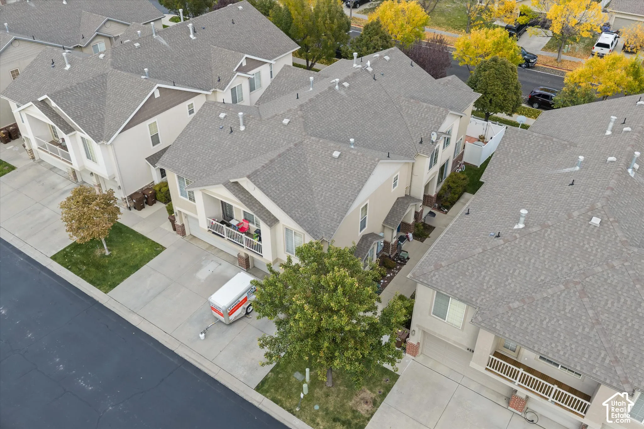 Aerial perspective of multi-story residences featuring composite shingle roofing, private balconies with railings, paved driveways, and exterior siding