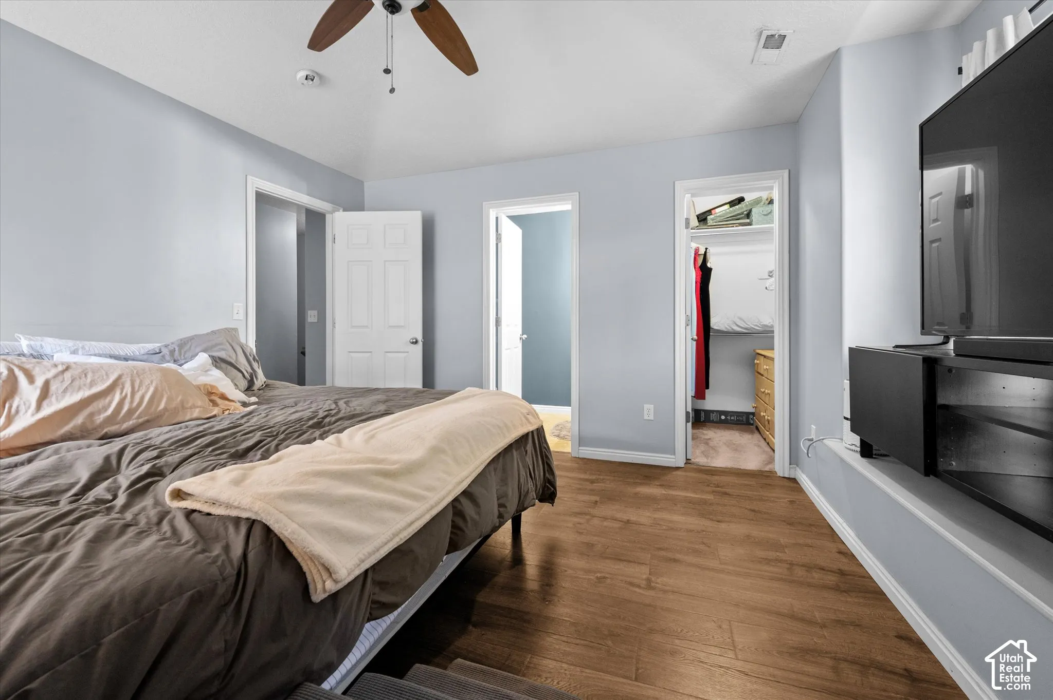 Vaulted ceilings, wood-finish flooring, ceiling fan with light fixture, and walk-in closet featuring built-in shelving