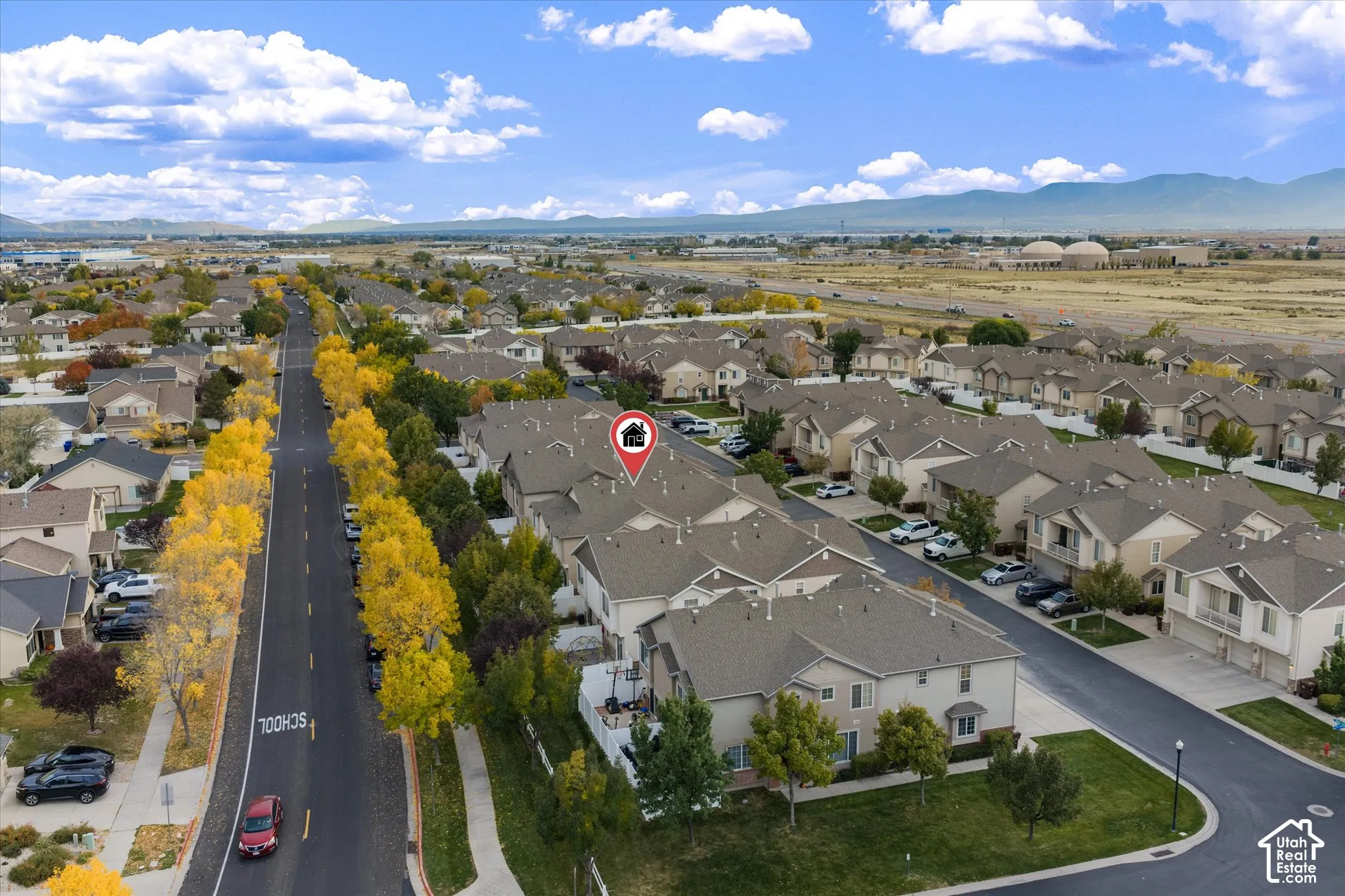 Aerial perspective featuring multi-story residential architecture with shingled roofing, paved streets, and a mountain backdrop