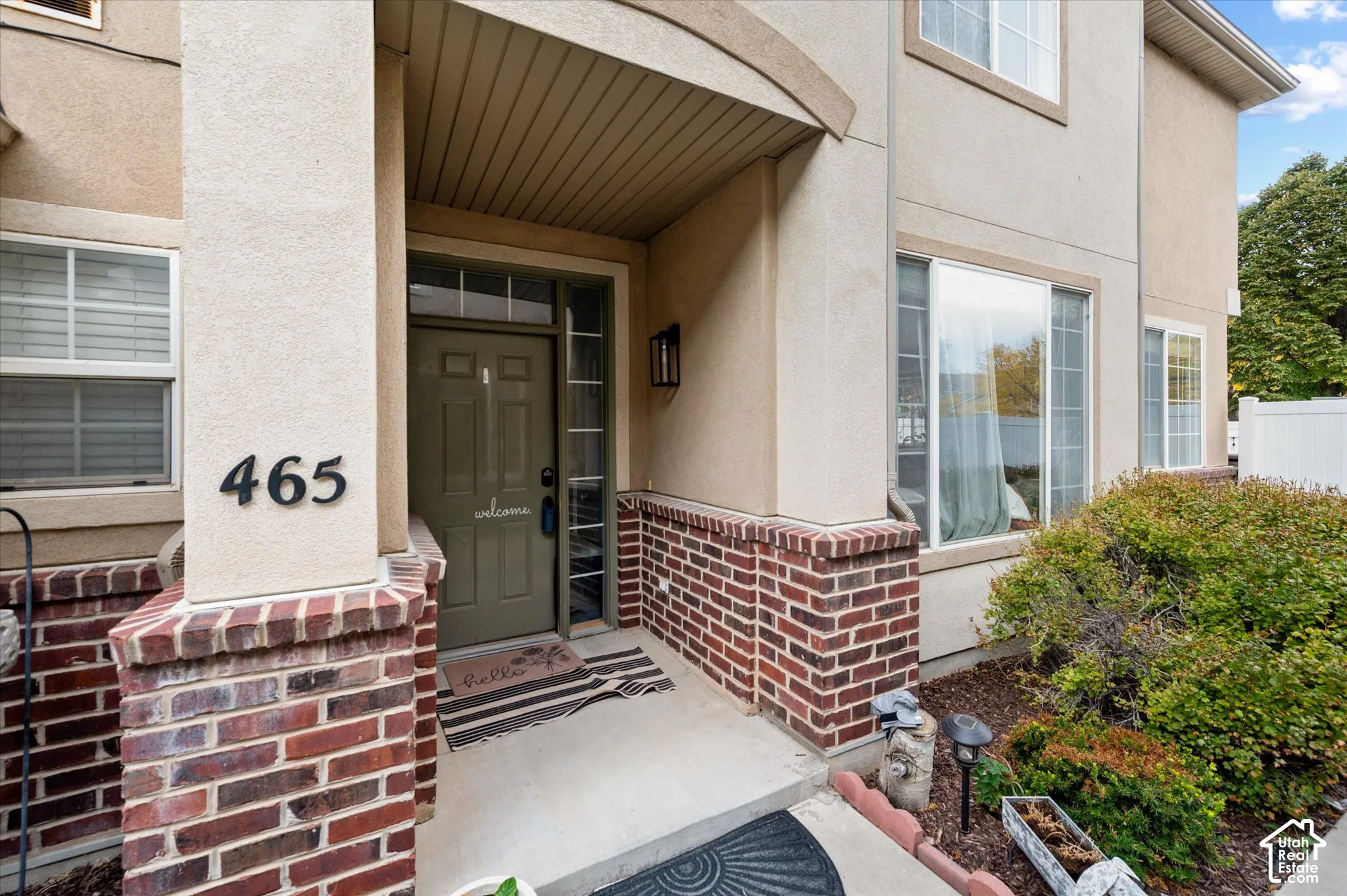 Covered entryway featuring masonry brick accents, a solid-paneled door with sidelight glass, and an exterior wall-mounted lantern light fixture