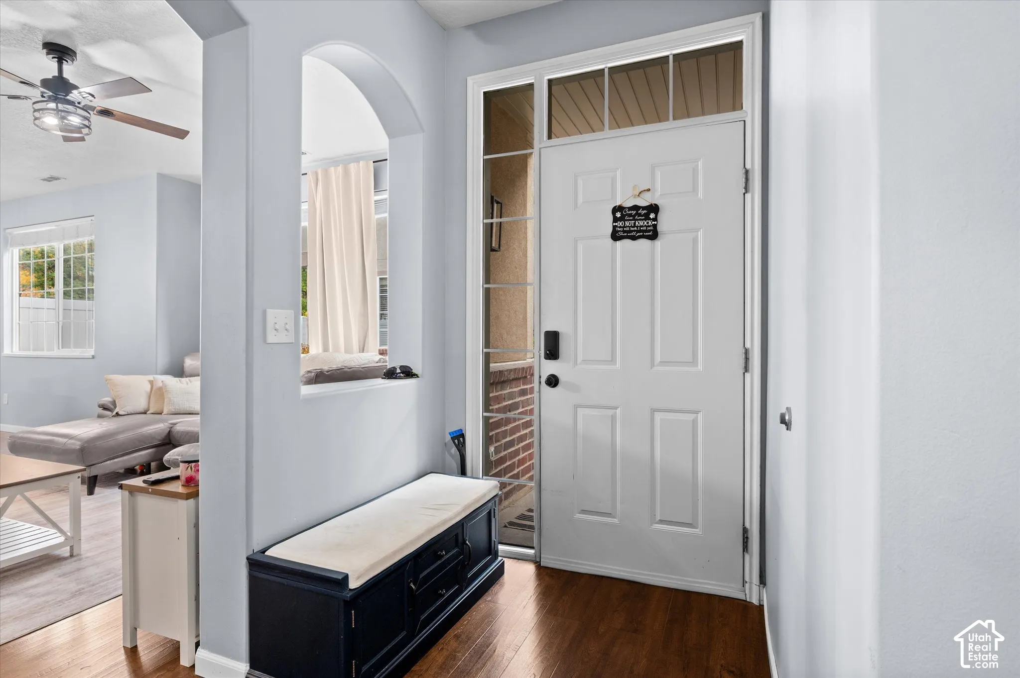 Entryway featuring a white paneled front door with a transom window and side light, wood-finish flooring, and an arched architectural cutout