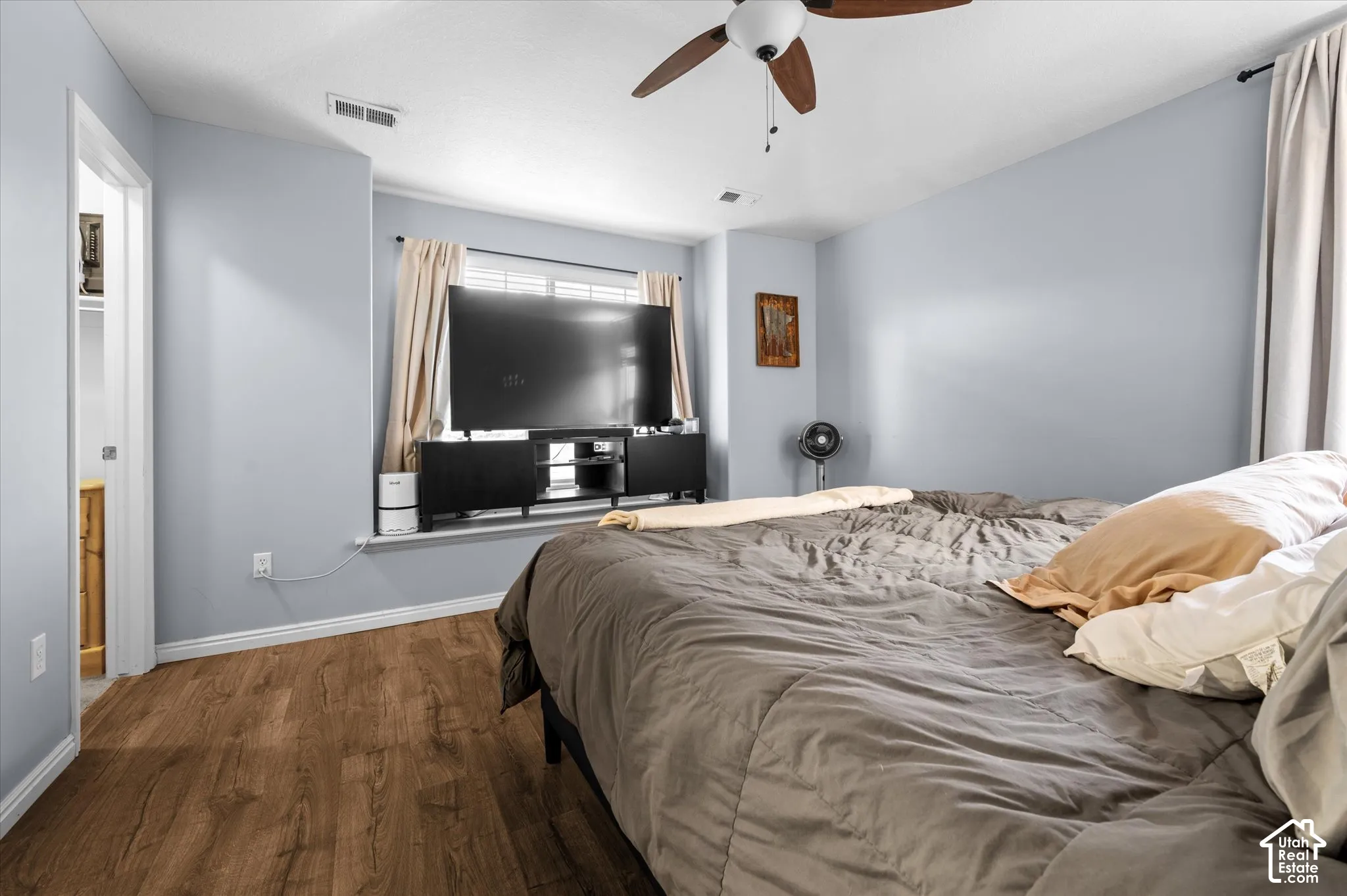 Room featuring wood-finish flooring, a ceiling fan with integrated lighting, and a window with a recessed sill