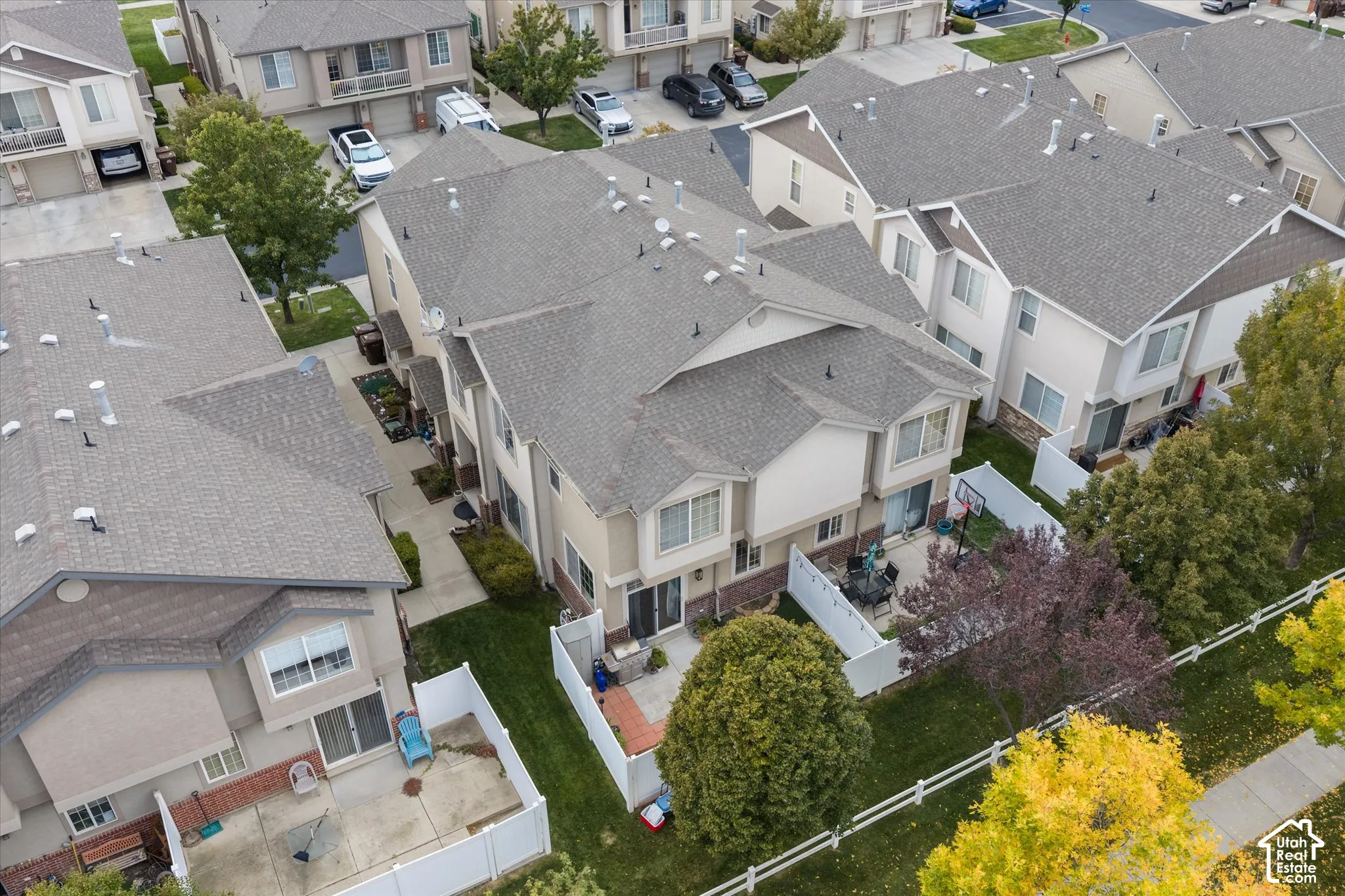 Multi-level townhouse exterior featuring a shingle roof, concrete patio, and private white vinyl fencing